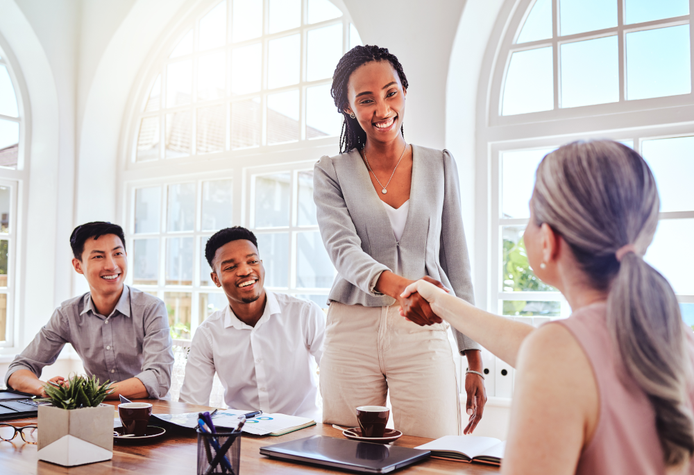 Employees shaking hands in a gesture of teamwork and collaboration, fostering a positive workplace culture and enhancing employee retention.